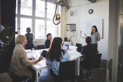 Businesswoman explaining colleagues during meeting in creative office