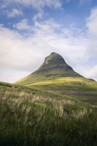 Low-angle view of kirkjufell mountain against briight cloudy sky, iceland, snæfellsnes peninsula