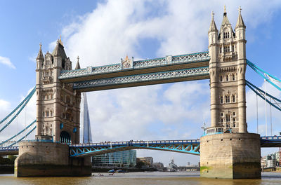 Low angle view of tower bridge over thames river against cloudy sky