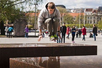 Young man jumping over seat in city