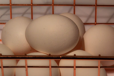 Close-up of white egg shells in copper basket  crate