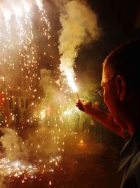 Close-up of man holding sparkler at night