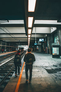 Rear view of people walking on railroad station platform