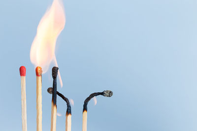 Close-up of lit candle against blue sky