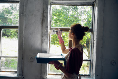 Side view of woman standing against window