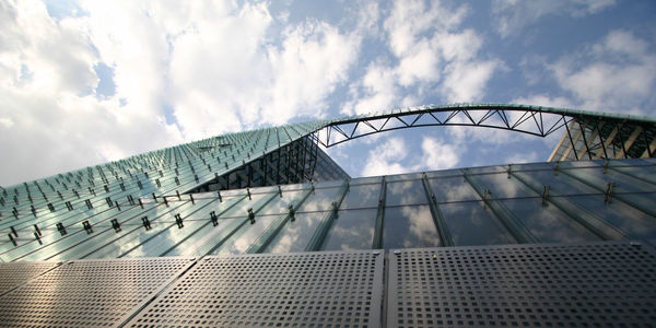 Low angle view of glass building against cloudy sky