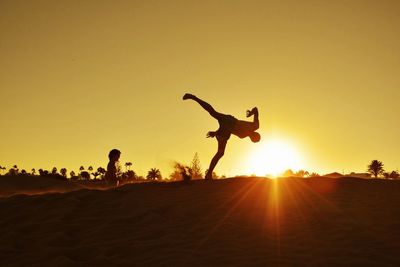 Silhouette of woman jumping at sunset