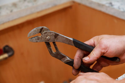 Close-up of cropped hand holding pliers at workshop