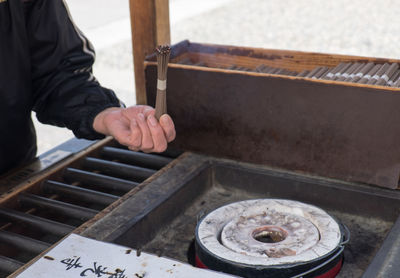 Person holding incense stick near prayer block