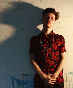 Portrait of handsome young man standing against wall