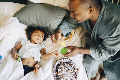 High angle view of father playing with daughter on bed at home