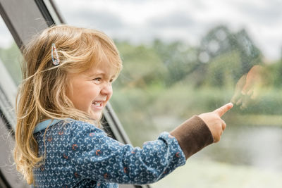 Cute smiling girl pointing on window