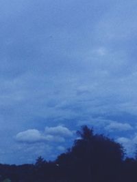 Low angle view of silhouette trees against blue sky