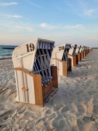 Hooded chairs on beach against sky