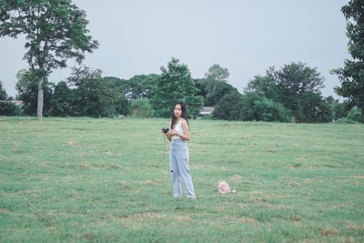 Full length of smiling woman standing on field