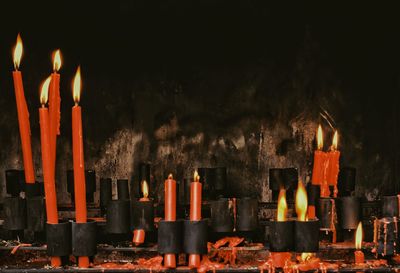 Illuminated candles in temple against wall