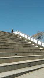 Low angle view of man walking on stairs against clear sky