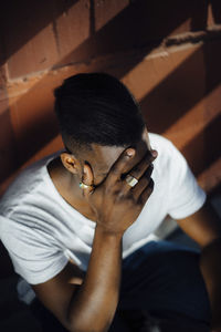 High angle view of sad man sitting against wall