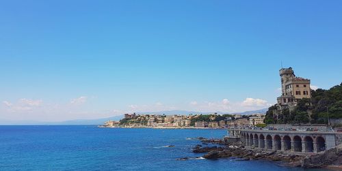 View of sea and buildings against blue sky