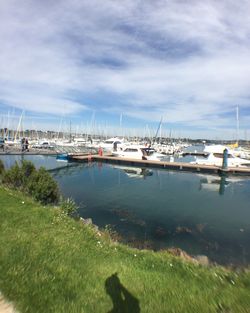 Boats in harbor against cloudy sky