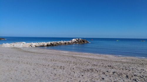 Scenic view of beach against clear blue sky