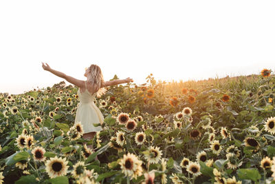 Woman standing by plants on field against sky