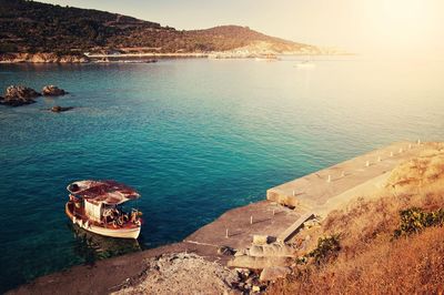 Boat moored in sea by mountain