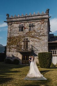 Couple standing by building against sky