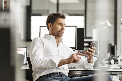 Businessman at desk in office using cell phone