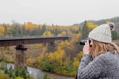 Woman photographing on camera against sky