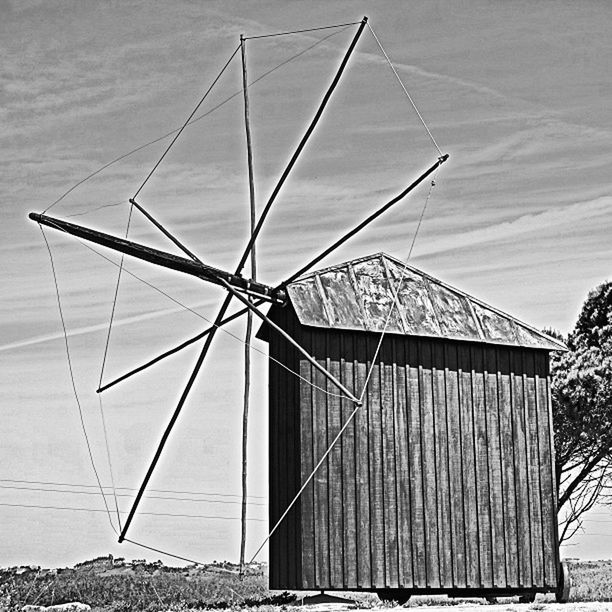 built structure, architecture, sky, building exterior, day, no people, outdoors, sunlight, environmental conservation, low angle view, wood - material, roof, fuel and power generation, white color, nature, alternative energy, cloud, shadow, flag, absence