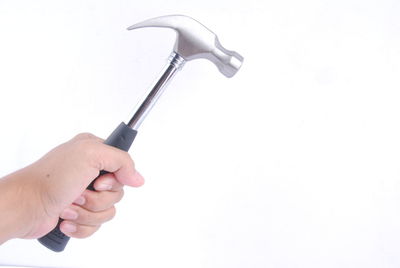 Close-up of hand holding ring against white background