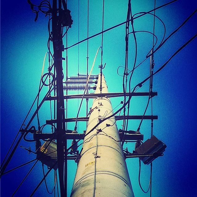 blue, low angle view, clear sky, built structure, electricity, technology, architecture, connection, electricity pylon, power line, sky, tall - high, fuel and power generation, sunlight, power supply, outdoors, metal, cable, tower, copy space