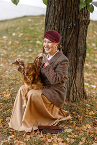 Side view of woman sitting on tree trunk