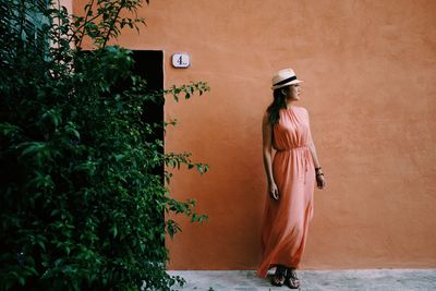 Woman standing by plants against building