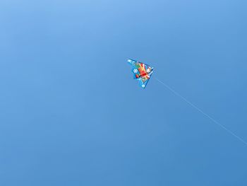 Low angle view of kite flying against clear blue sky