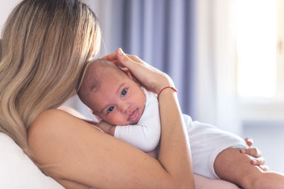 Close-up of woman holding son while sitting at home