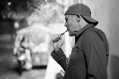 Side view of man smoking cigarette outdoors