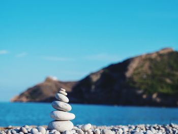 Stack of pebbles on beach against clear blue sky