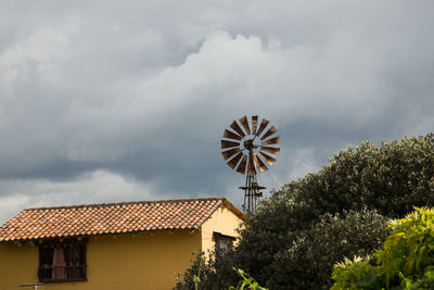 Traditional windmill on roof of building against sky