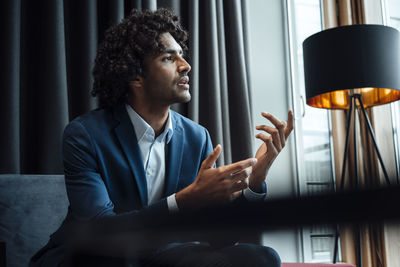 Confident handsome male professional gesturing while sitting in office