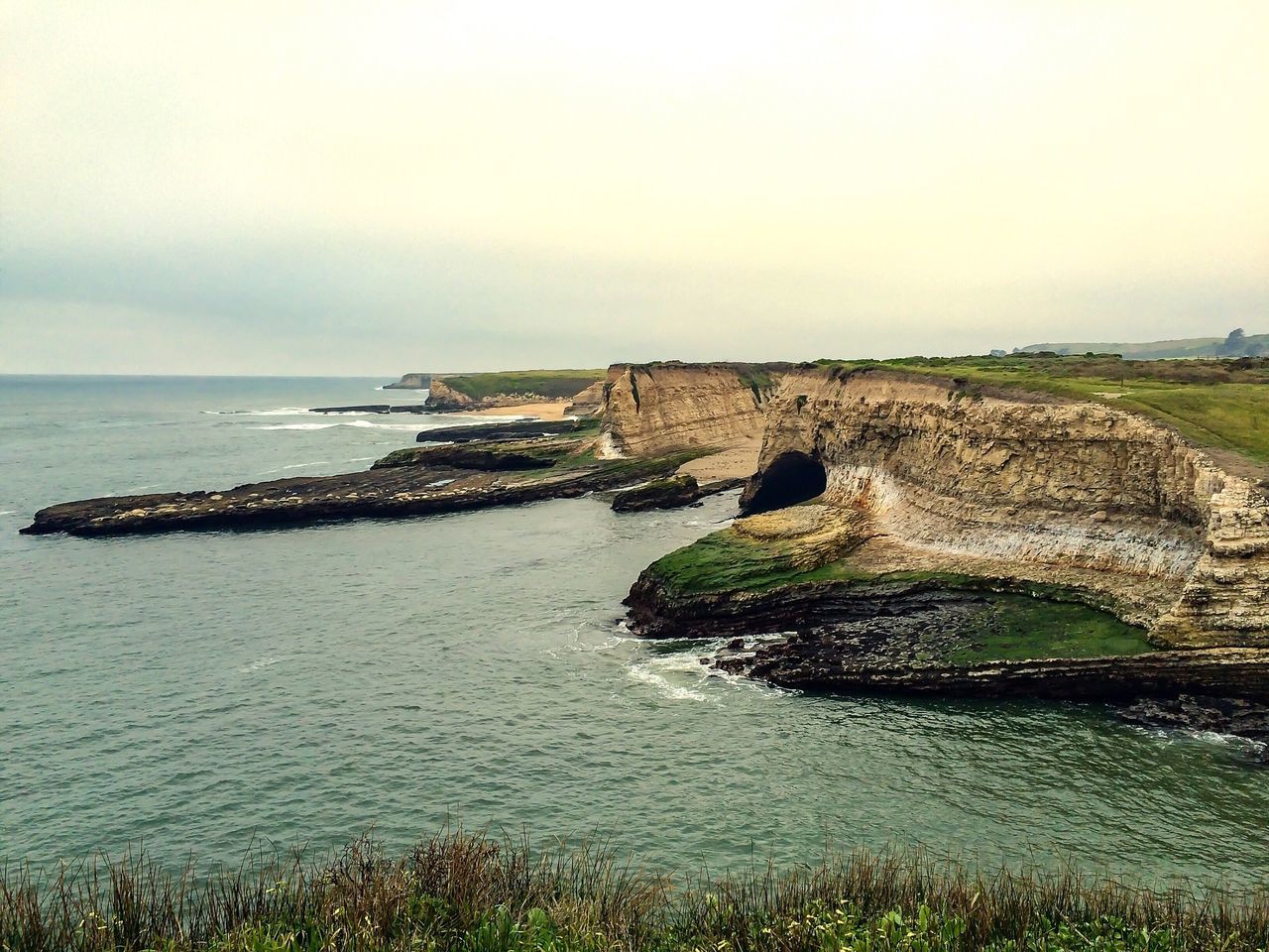 sea, water, horizon over water, tranquil scene, tranquility, scenics, sky, rock - object, nature, beauty in nature, rock formation, cliff, grass, coastline, rock, idyllic, built structure, day, travel destinations, outdoors