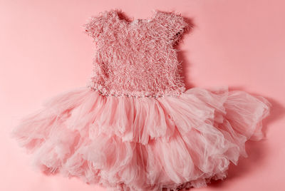 Close-up of wedding dress against pink background