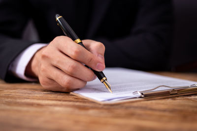 Cropped image of man holding paper on table