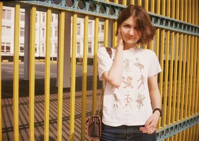 Portrait of woman standing against railing