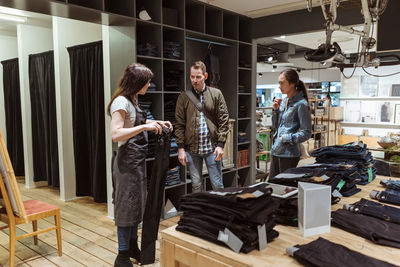 Saleswoman showing jeans to customers at store
