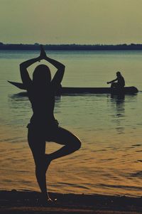 Silhouette people on shore against sea during sunset