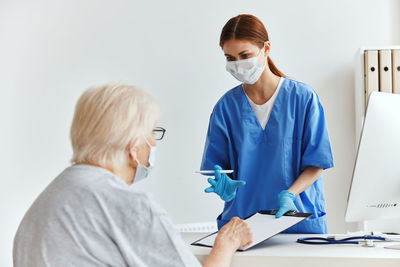 Doctor wearing mask examining patient at hospital