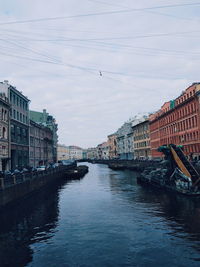 Birds flying over river in city against sky