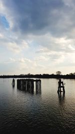 Silhouette pier on lake against sky